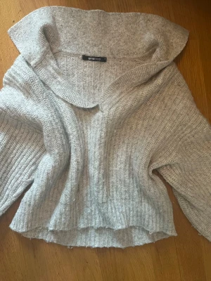 Ljusgrå stickad tröja Gina Tricot - Mysig ljusgrå stickad tröja från Gina Tricot med bred krage och avslappnad passform. Tröjan har ribbstickat mönster. Perfekt för lager på lager och chill dagar.