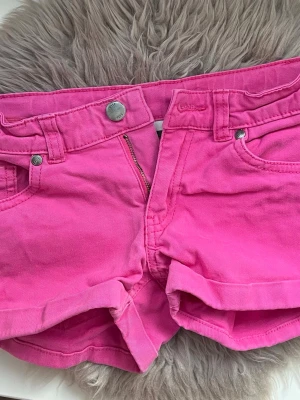 Rosa jeansshorts  - Snygga rosa jeansshorts med klassisk femficksdesign och uppvikta benslut. låren är ungefär 42cm och midjan platt 32cm