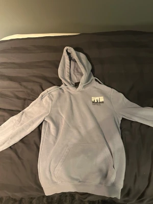 Ljusgrå hoodie med tryck - Ljusgrå hoodie med huva och känguruficka. På bröstet finns ett litet tryck och på ryggen ett större tryck med texten 'GLOBAL MINDSET' och motiv av kaktusar och streckkod. Mjuk bomullskänsla och avslappnad passform, perfekt för chill dagar.