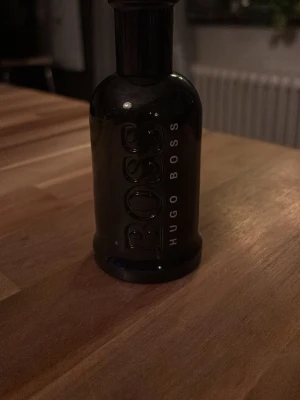 Hugo Boss Bottled Eau de Toilette 100ml - Snygg parfymflaska från Hugo Boss i svart glas med tydlig BOSS-logga. Flaskan rymmer 100 ml och har en stilren, maskulin design. Perfekt för dig som gillar klassiska och eleganta dofter. Eau de Toilette-variant. Just denna parfym har över halva flaskan kvar. Minst 70% kvar. 