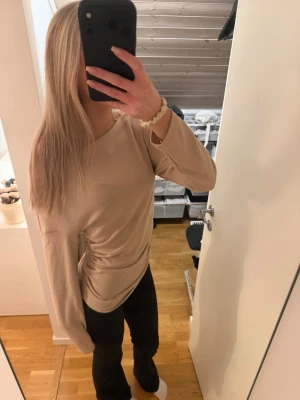Beige långärmad tröja basic - Säljer en enkel och stilren beige långärmad tröja med rund hals. Tröjan har en rak passform och är tillverkad i ett mjukt material som känns skönt mot huden. Perfekt att matcha med jeans eller leggings för en clean look.