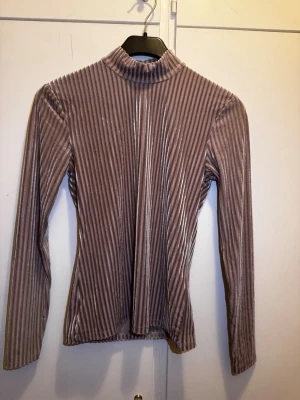 Ribbad beige polotopp i sammet - Säljer en beige ribbad polotopp i mjuk sammet. Toppen har lång ärm och en hög krage. Har endast använts en gång.