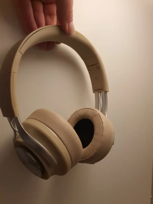 Beige hörlurar från Nordic - Stilrena hörlurar i beige från Nordic med mjuka, vadderade kåpor och justerbart huvudband. Hörlurarna har detaljer i metall och en modern, minimalistisk design som passar perfekt till vardagslyssning och gaming.