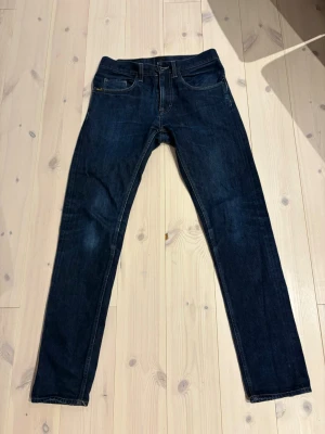 Tiger of sweden  - Säljer ett par mörkblå jeansbyxor från Tiger of Sweden i modellen Pistolero. Klassisk femficksdesign, raka ben och snygga kontrastsömmar. Jeansen har en mörk tvätt och är tillverkade i slitstarkt denimtyg. Perfekta för dig som gillar en enkel och clean look.