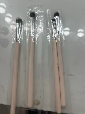 Set med fyra ögonskuggsborstar - Säljer ett set med fyra ögonskuggsborstar med ljusbeige träskaft och silverfärgat metallfäste. Borsthuvudena är täta och mjuka, perfekta för att blenda och applicera ögonskugga. Alla borstar är individuellt förpackade i plast. Fick i hickaps jul kalender. Använder ej där av säljer jag. 