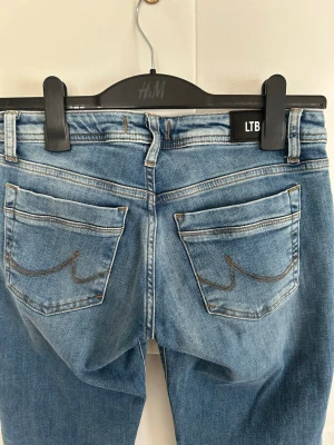 Blå valerie jeans från LTB - Snygga blå jeans från LTB med bootcut och klassisk femficksdesign. Jeansen har ljusa slitningar framtill och bakficka med dekorativ söm. Modell Valerie, storlek 27/32. Knappt använd