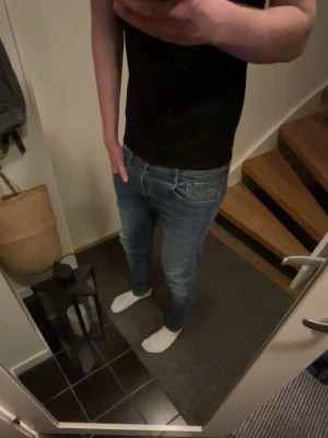 Replay ljusblå jeans herr - Ljusblå jeans från Replay med klassisk femficksdesign och diskreta slitningar. Jeansen har raka ben och detaljerade sömmar på bakfickorna. Tillverkade i denim med en något tvättad look och orangea sömmar.