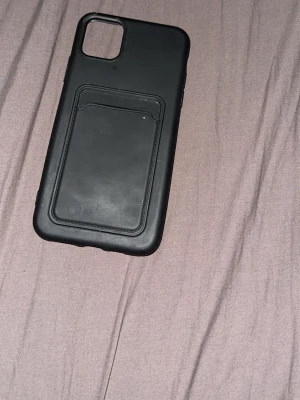 Svart mobilskal med kortfack - Snyggt svart mobilskal med inbyggt kortfack på baksidan. Skalets design är stilren och praktisk, perfekt för dig som vill ha både skydd och plats för kort. Tillverkat i tåligt material som ger bra grepp och skydd till din mobil.