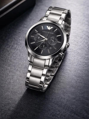 Emporio Armani silverfärgad klocka - Stilren klocka från Emporio Armani med svart urtavla och silverfärgat armband i metall. Klockan har kronograf-funktion och klassisk design med märkets logga högst upp på urtavlan. Perfekt accessoar för dig som gillar en tidlös och elegant look.
