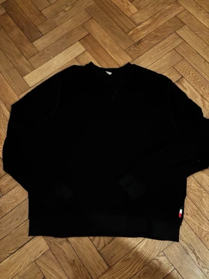 Svart sweatshirt från Moncler - Säljer en svart sweatshirt från Moncler med klassisk rund halsringning och är en del av black badge kollektionen. Liten broderad logga i rött, vitt och blått vid nederkanten. Perfekt för en clean och stilren look. Släpptes 2020 