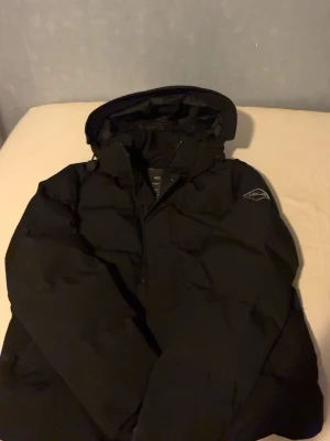 Svart dunjacka från Replay har kvitto pris kan diskuteras - Snygg svart dunjacka från Replay med huva och diskret logga på ärmen. Jackan är av modellen 'Heavy Weight', perfekt för kalla dagar. Mountain inspired-design och tillverkad i tekniskt material som håller värmen. Praktisk och stilren för vintern.