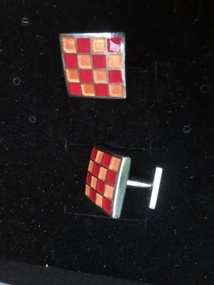 Rutiga manschettknappar från Pink - Säljer ett par fyrkantiga manschettknappar från Pink med schackrutigt mönster i rött och guld. Metallramen ger en stilren touch och de passar perfekt för att lyfta skjortan med lite färg och personlighet. Kommer i originalask.
