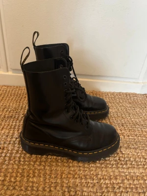 Svarta Dr. Martens boots i läder - Säljer ett par klassiska svarta Dr. Martens 1460 Bex i skinn med snörning och gul söm runt. Mycket bra skick, nypris 2300 kr.