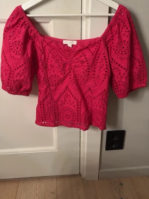 Rosa offshoulder topp från H&M - Snygg rosa  topp från H&M i storlek 34. Toppen har puffiga korta ärmar och är dekorerad med broderade detaljer och hålmönster. Perfekt för dig som vill ha en feminin och trendig look.  