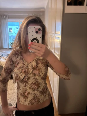 Spetstopp med volang och omlottdesign! - Söt blommig topp med volang längs ringningen. Den är trekvartsärmad och har en olmottdesign. Köpt secondhand. Perfekt nu till våren!!🌸