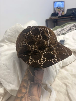 Brun Gucci keps med GG-mönster - Säljer en riktigt fet Gucci-keps i brun färg med klassiskt GG-monogram. Mjuk sammet/velour-känsla som ger en lyxig look – sitter bra och sticker ut direkt.  ✔ Stilren & exklusiv ✔ Bra skick (se bilder) ✔ Perfekt till både vardag & outfit när man vill flexa lite  📦 Kan skickas eller mötas upp  ❌ Inga byten  Skriv om du vill ha fler bilder eller snabb affär 💯