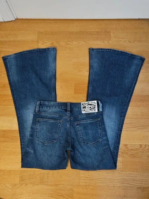 Låg midja utsvängda jeans från Cheap Monday - Säljer ett par blå flare low jeans från Cheap Monday med tydlig logga bak i midjan. Jeansen är helt nya. Storlek W27 på jeansen men passar som W25 om man jämför med andra märken. Pris kan diskuteras 🫶