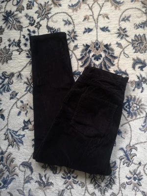 Svarta Manchesterbyxor Från Monki Stl M - Snygga svarta manchesterbyxor, använts ett fåtal gånger, hög midja, i fin skick, rök och djurfri hem. Lappen finns inte kvar. stl 32 inch, 82 cm midja. 106cm längd.