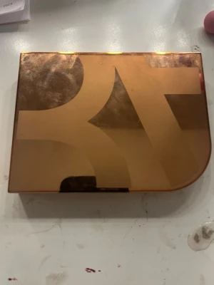 Bronzerpalett från Rare Beauty - Snygg bronzerpalett från Rare Beauty i en lyxig, kopparfärgad förpackning. Paletten innehåller fyra nyanser i bruna och beige toner, perfekt för att skapa dimension och värme i ansiktet. Kommer med stor spegel i locket för enkel applicering.