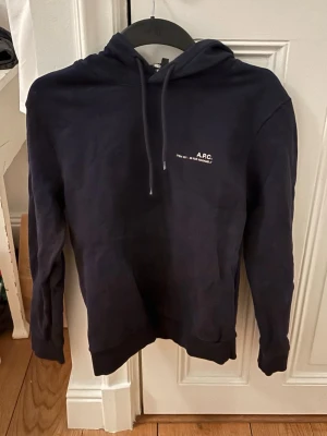 Mörkblå hoodie från A.P.C. - Snygg mörkblå hoodie från A.P.C.  Hoodien är för liten för mig vilket är drf ja säljer den(s). Hoodien är i sjukt bra skick de vill säga inga hål och sånt. Pris kan diskuteras vid snabbt köp
