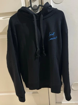 Svart hoodie med blå text från Saint Laurent - Säljer en helt ny svart hoodie från Saint Laurent med blå text. Sällsynt modell. Liten i storlek passar som en storlek S. Pris kan diskuteras vid snabb affär. Fraktas inom 48 timmar efter köp🚛📦