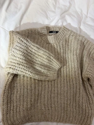 Beige chunky stickad tröja Bik Bok - Säljer en beige chunky stickad tröja från Bik Bok i storlek M. Tröjan har grov ribbstickning, rund halsringning och långa ärmar. Perfekt för kalla dagar och superenkel att styla med jeans eller kjol.