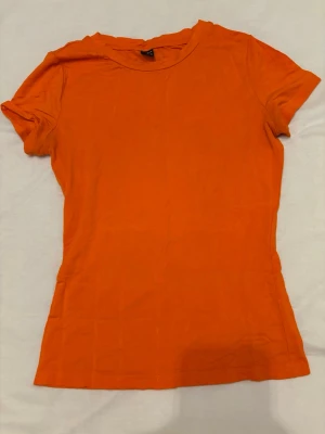 Orange t-shirt från SHEIN - En enkel och snygg orange t-shirt från SHEIN i storlek S. T-shirten har rund halsringning och korta ärmar. Tillverkad i mjukt material som känns skönt mot huden. Perfekt att matcha med jeans eller kjol för en avslappnad look.