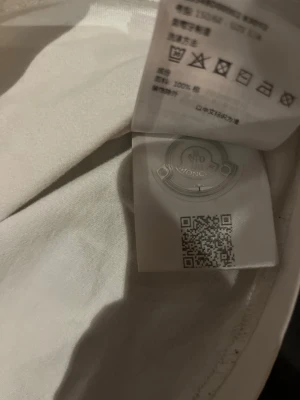 Vit t-shirt från Moncler i bomull - Snygg vit tröja från moncler som jag säljer för 445kr pga ett litet hål vid halsen som man knappt ser och en liten fläck som inte går bort. Men 100% äkta köpt på NK i Stockholm passar 150/155 ish skriv vid intressen