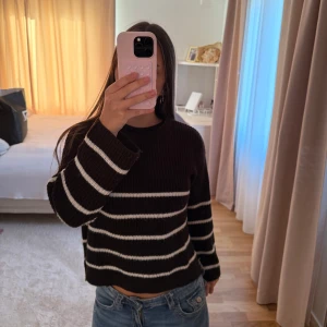 Svartvit randig stickad tröja - Säljer en svart stickad tröja med vita horisontella ränder. Tröjan har en rund hals och långa ärmar med breda muddar. Den är loose fit och passar perfekt till jeans för en chill och snygg look.