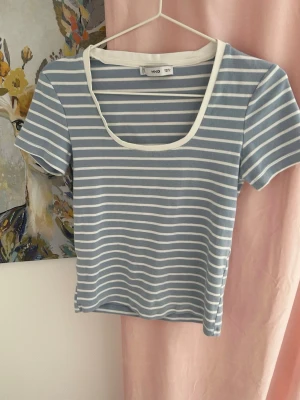 Randig blå och vit topp från MNG - Superfin topp från Mango i blått och vitt med smala ränder. T-shirten har korta ärmar, rundad urringning med vit kant och en croppad passform. 🐬🫧🦋