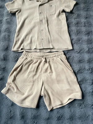 Beige sommarsät från Kappahl  - Säljer ett beige klädställ, skjorta och shorts. Passar perfekt för sommarkvällar med extra stil. Skönt material samt fint material, perfekt inför sommaren.