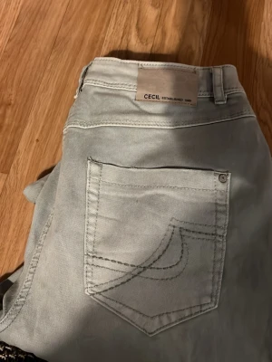 Ljusgrå jeans från Cecil - Snygga ljusgrå jeans från Cecil med klassisk femficksmodell och raka ben. Jeansen har dekorativa sömmar på bakfickan och är tillverkade i ett mjukt denimtyg. Perfekta för en avslappnad och trendig look.