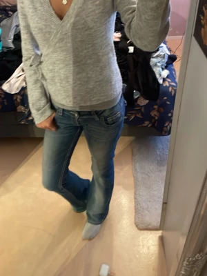 Grå stickad tröja med v urringning  - Säljer min gråa stickade knyttröja ifrån lager157 i storlek s. Man knyter den på båda sidorna och får en fin V urigning. Föredrar att ha linne under men passar jätte bra utan