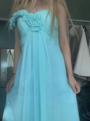 Ljusblå balklänning med oneshoulder - Superfin ljusblå långklänning med oneshoulder och vackra volangdetaljer över axeln. Klänningen har en romantisk och flowy passform, perfekt för speciella tillfällen. Tillverkad i ett lätt och luftigt material som ger en elegant känsla. Skriv om du vill ha mått eller fler bilder❣️