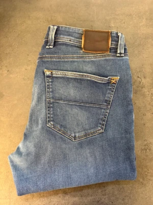 TRAMAROSSA Leonardo jeans  - Snygga blå slim fit jeans från TRAMAROSSA med klassisk femficksdesign och läderpatch bak i midjan. Jeansen har raka ben och är tillverkade i mjukt denimtyg med lätt tvättad look. Perfekta för en avslappnad och trendig stil. Mått  Midja (platt): 44 cm Innerbenslängd: 76 cm Lårvidd (10 cm från gren): 24,5 cm Benöppning: 16 cm Grenhöjd: 25,5 cm Total längd: 101 cm