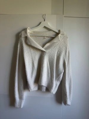 Vit stickad tröja med krage H&M XS - Mysig vit stickad tröja från H&M i storlek XS. Tröjan har en avslappnad passform, lång ärm och en bred krage.