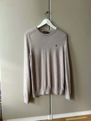 Beige tröja från Morris - Klassisk beige tröja från Morris med rund halsringning och diskret logga broderad på bröstet. 100% Merino ull.