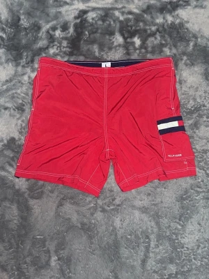 Tommy Hilfiger Badbyxor – Röda - ett par fräscha röda badshorts från Tommy Hilfiger. Fina marina detaljer och vita sömmar. med alla tvättlappar kvar.   toppskick, inga defekter.  