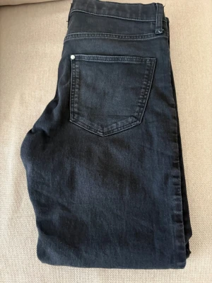 Svarta slim fit jeans med adjustable waist från H&M - Snygga svarta slim fit jeans från H&M med justerbar midja. Klassisk femficksmodell och raka ben. Perfekta för dig som gillar en smalare passform och stilren look.