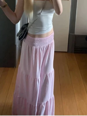 Ljusrosa långkjol - Säljer en ljusrosa långkjol. Kjolen har en luftig passform, perfekt för varma dagar. Enkel att matcha med olika toppar för en chill och trendig look. Den är från lager 157 men säljs nog inte längre. Har använt den 1 gång
