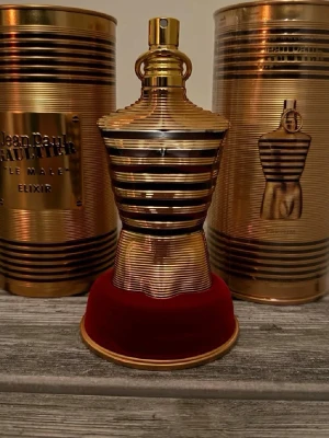 Jean Paul Gaultier Le Male Elixir - Exklusiv parfym i en ikonisk flaska formad som en manlig torso, med guld- och svartfärgade ränder. Kommer i en lyxig metallisk förpackning med matchande detaljer. Perfekt för dig som gillar unika och snygga flaskor.