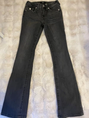 Grå Svarta jeans från True religion - Snygga och trendiga jeans från True Religion, modell Becca Mid Rise Bootcut. Klassisk svart tvätt som passar till allt, med smickrande passform och lätt utsvängda ben (bootcut). Perfekta för en Y2K-inspirerad look eller vardagsstil.