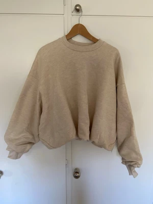 Beige oversized sweatshirt från Arrange, Asos  - Säljer en beige oversized sweatshirt från Arrange, Asos, med rund halsringning och långa, vida ärmar. Tröjan har en tajtare passform där nere med en ”scunched” look. Helt ny med prislapp. 