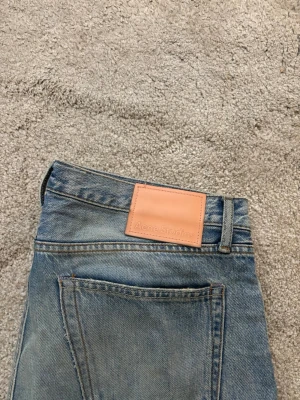 Acne Studios jeans - Ljusblå raka jeans från Acne Studios, modell 1996 Light Blue Trash. Klassisk femficksmodell med slitningar. Tillverkade i 100% bomull för en autentisk jeanskänsla. Snyggt tvättade med vintage-vibe och Acne-läderpatch bak.