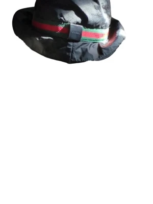 Svart bucket hat - Snygg svart bucket hat med klassiskt grönt och rött band runtom. Hatten är tillverkad i Italien och har en mjuk, lätt glansig yta. Perfekt accessoar för dig som vill sticka ut med en ikonisk och trendig look. Står storlek m men uppskattar en xs-s