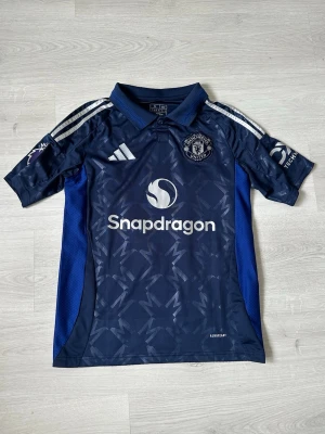 Manchester United S - Säljer en snygg och stilren Manchester United-tröja i fint skick – perfekt för både matchdagar och vardagsstil! 🔴⚽ Tröjan är bekväm, av hög kvalitet och ett måste för alla fans av klubben.  Passa på att uppdatera din supporter-garderob eller ge bort en uppskattad present till någon som älskar fotboll!  👉 Kika gärna in min profil – jag säljer fler fotbollströjor i olika modeller och storlekar. 💥 Rabatt erbjuds vid köp av flera plagg!  Hör av dig vid frågor eller intresse! 