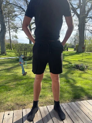 Svarta shorts med snörning - Svarta shorts med midja och snörning i midjan. Klassisk och enkel design, perfekt för sommardagar. Shortsen har en normal passform och är tillverkade i ett mjukt material som känns bekvämt mot huden.