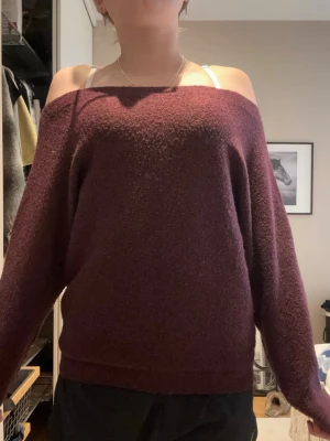 Bordeaux off shoulder stickad tröja - Mysig bordeaux stickad tröja med off shoulder-design och avslappnad passform. Tröjan har långa ärmar och bred halsringning som ger en trendig look. Perfekt för lager-på-lager och chill dagar.