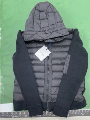 Nfc moncler cardigan  - Snygg svart pufferjacka från Moncler med quiltad framsida och huva. Jackan har stickade ärmar och rygg i mjukt material, dragkedja framtill och Moncler-logga på ärmen. Perfekt för kalla dagar och ger en sportig look. Nfc funkar✅