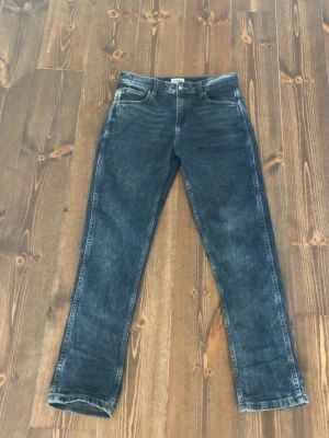 Mörkblå jeans från Wrangler - Snygga mörkblå jeans från Wrangler med klassisk femficksmodell och raka ben. Jeansen har tydliga kontrastsömmar och ikonisk W-brodering på bakfickorna. Tillverkade i slitstark denim som ger en cool vintagekänsla. Passar också s har använt dom 3 gånger har inga skador